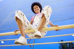 mulher negra sorridente sentada em cima do muro na cidade foto