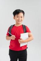 menino de escola com mochila escrevendo algo em seu caderno, isolado no branco. foto