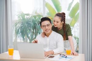 livro online. mulher atraente feliz abraçando o homem enquanto ele usa o laptop foto