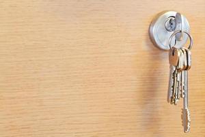 molho de chaves em casa na fechadura da porta de madeira foto