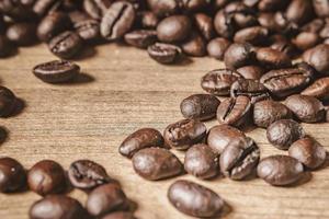 café em fundo de madeira. grãos de café torrados marrons, sementes em fundo escuro. expresso escuro, aroma, bebida de cafeína preta. closeup isolado energia mocha, ingrediente cappuccino. foto