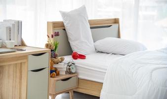 o design interior moderno ou minimalista do quarto decorado com cama de casal confortável, roupa de cama branca, como cobertor, travesseiros e móveis de madeira foto