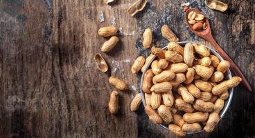 amendoins secos ou nozes em fundo de madeira cascas de amendoim em uma colher de pau