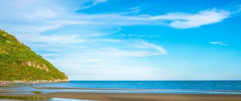 belas paisagens do mar com montanhas e lindo céu azul, praia de areia de manhã. foto