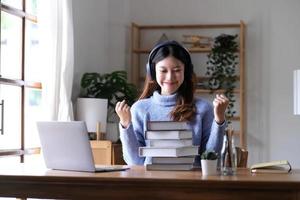 mulher asiática comemora com laptop, pose feliz de sucesso. e-commerce, educação universitária, tecnologia de internet ou conceito de pequena empresa de inicialização. escritório moderno ou sala de estar com espaço de cópia foto