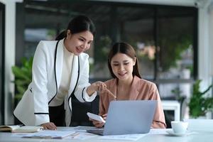 duas jovens empresárias asiáticas conversam, consultam, discutem o trabalho com a nova apresentação da ideia do projeto de inicialização analisam o plano de marketing e investimento no escritório. foto