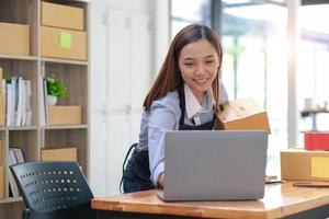 PME empreendedora jovem garota freelance asiática trabalha com um laptop e caixa em casa, sobre comércio eletrônico, negócios, vendedor, asiático, funcionário, empresário, caixa, comerciante, ideias de negócios online para PME, foto