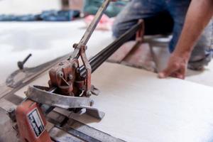 trabalhador cortando as telhas cerâmicas de efeito de madeira foto