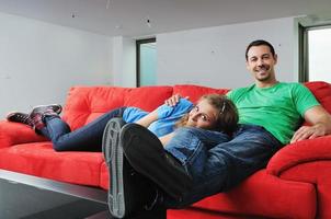 casal feliz relaxa no sofá vermelho foto