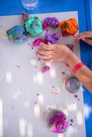 mãos de criança brincando com argila colorida foto