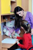 mãe e filha fazendo lição de casa em casa foto