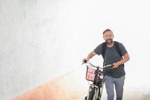 homem hipster com uma mochila empurrando uma bicicleta retrô foto