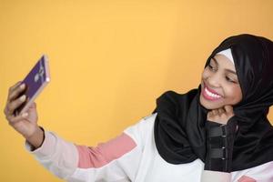 mulher muçulmana africana com um lindo sorriso tira uma selfie com um telefone celular foto