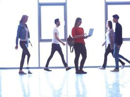 aluna de pé com laptop, grupo de pessoas passando foto