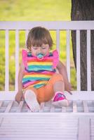 menina bonitinha sentada no banco de madeira