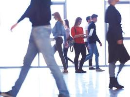 aluna de pé com laptop, grupo de pessoas passando foto