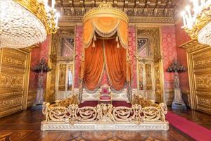 antigo interior da sala do trono com cadeira no palácio de luxo. estilo barroco antigo vermelho e dourado. foto