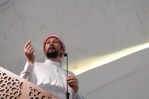 o jovem imã árabe muçulmano faz um discurso na oração da tarde de sexta-feira na mesquita. foto