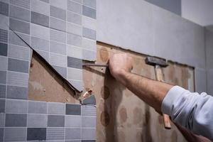 trabalhador remover demolir azulejos antigos em um banheiro foto