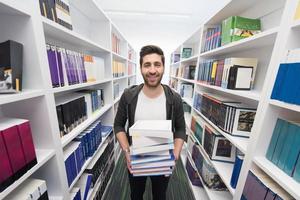 estudante segurando muitos livros na biblioteca da escola foto