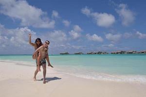 feliz casal jovem se divertir na praia foto