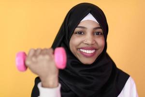mulher afro muçulmana promove uma vida saudável, segurando halteres nas mãos foto