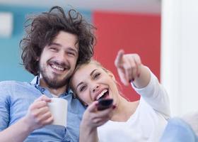 jovem casal no sofá assistindo televisão foto