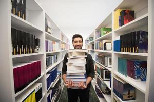 estudante segurando muitos livros na biblioteca da escola foto