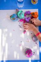 mãos de criança brincando com argila colorida foto