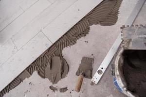 telhas de efeito de madeira cerâmica e ferramentas para ladrilhador no chão foto
