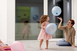 mãe e filha pequena brincando com balões foto