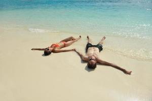 feliz casal jovem se divertir na praia foto