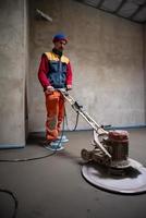 trabalhador realizando e polindo piso de betonilha de areia e cimento foto