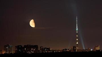 meia lua sobre torre de tv e cidade na noite de verão foto