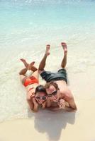 feliz casal jovem se divertir na praia foto