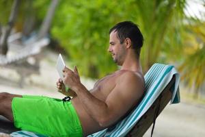 homem relaxando e use tablet na praia foto