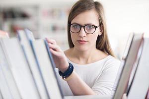 retrato de estudante famale selecionando livro para ler na biblioteca foto