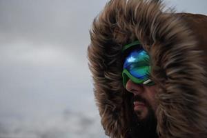 homem no inverno em clima de tempestade, vestindo jaqueta de pele quente foto