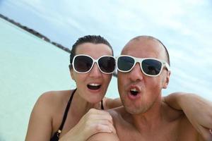 feliz casal jovem se divertir na praia foto