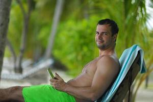 homem relaxando e use tablet na praia foto