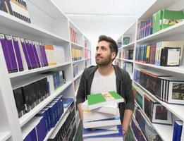 estudante segurando muitos livros na biblioteca da escola foto