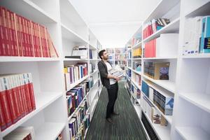 estudante segurando muitos livros na biblioteca da escola foto