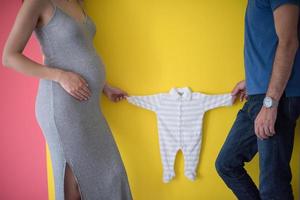 jovem casal segurando roupas de bebê foto