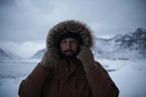homem no inverno em clima de tempestade, vestindo jaqueta de pele quente foto