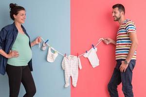 jovem casal segurando roupas de bebê foto