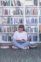 Famale estudante lendo livro na biblioteca foto