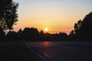 amanhecer sobre a estrada que leva para a floresta escura foto