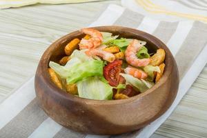 salada caesar com camarões em uma tigela sobre fundo de madeira foto