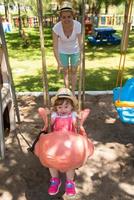 mãe e filha balançando no parque foto