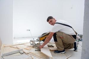 homem cortando prancha de piso laminado com serra circular elétrica foto